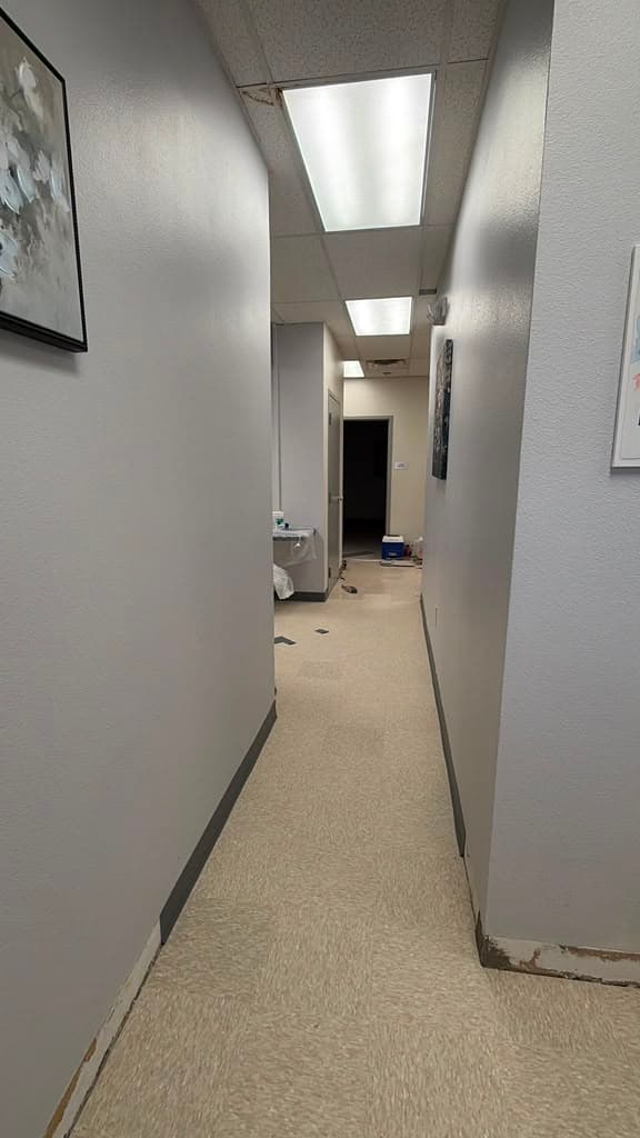 Completed corridor with new flooring and cove base installed in an El Paso medical office, artwork rehung and the space back in service.